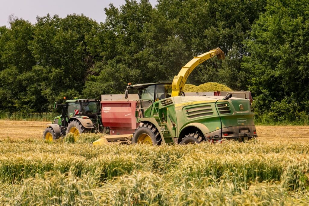 Two tractors harvesting wheat in sunny Croatian countryside during summer.