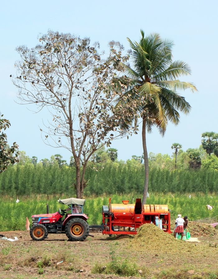 Vibrant rural scene with a tractor, farming machinery, and lush greenery.